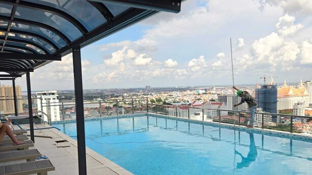 Una piscina sul tetto con soffitto in vetro, poltrone relax e vista sulla città.