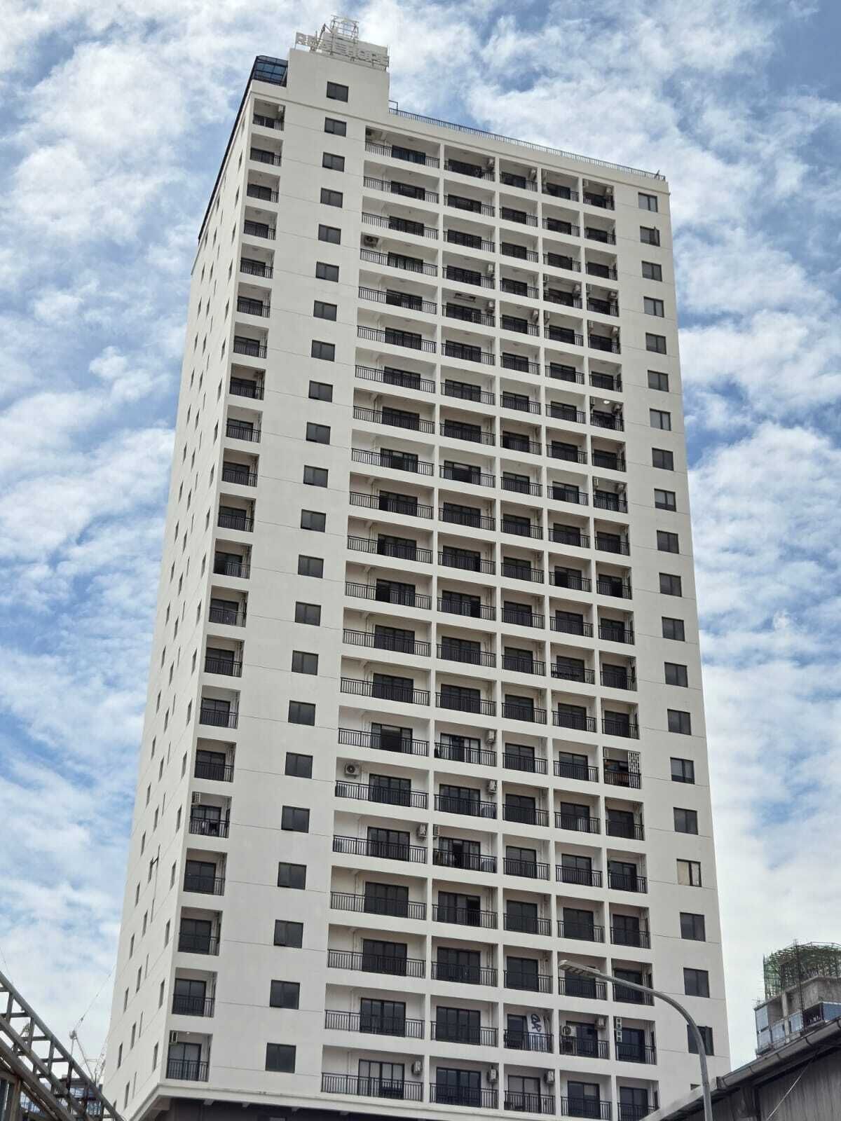 Un grand bâtiment blanc, doté de nombreux balcons et fenêtres, qui ressemble probablement à un hôtel ou à un immeuble d’appartements.
