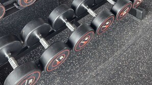 Una palestra con file di manubri neri con segni rossi e bianchi, un tapis roulant e una panca per pesi.