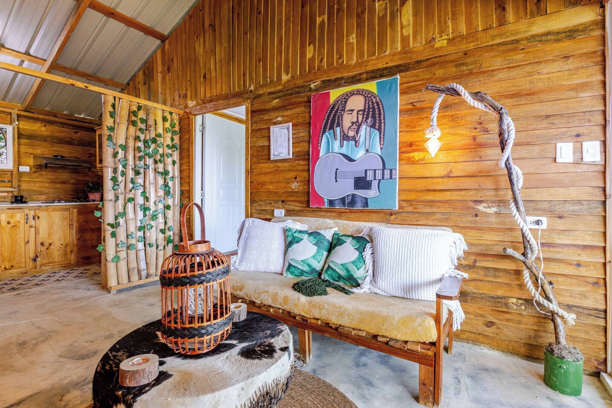 A wooden interior with a sofa, a hanging light, and a wall with a guitar painting.