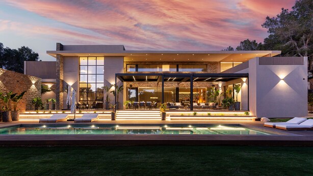 A modern house with a pool, outdoor seating, and a large glass door. - New build villa right on the beach with tropical garden and Bali feeling (Cala Vinyes)