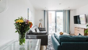 A modern living room with a sofa, a coffee table, and a TV. - Beautiful 1 Bedroom Waterfront Apartment with parking in Gloucester Docks (Gloucester)
