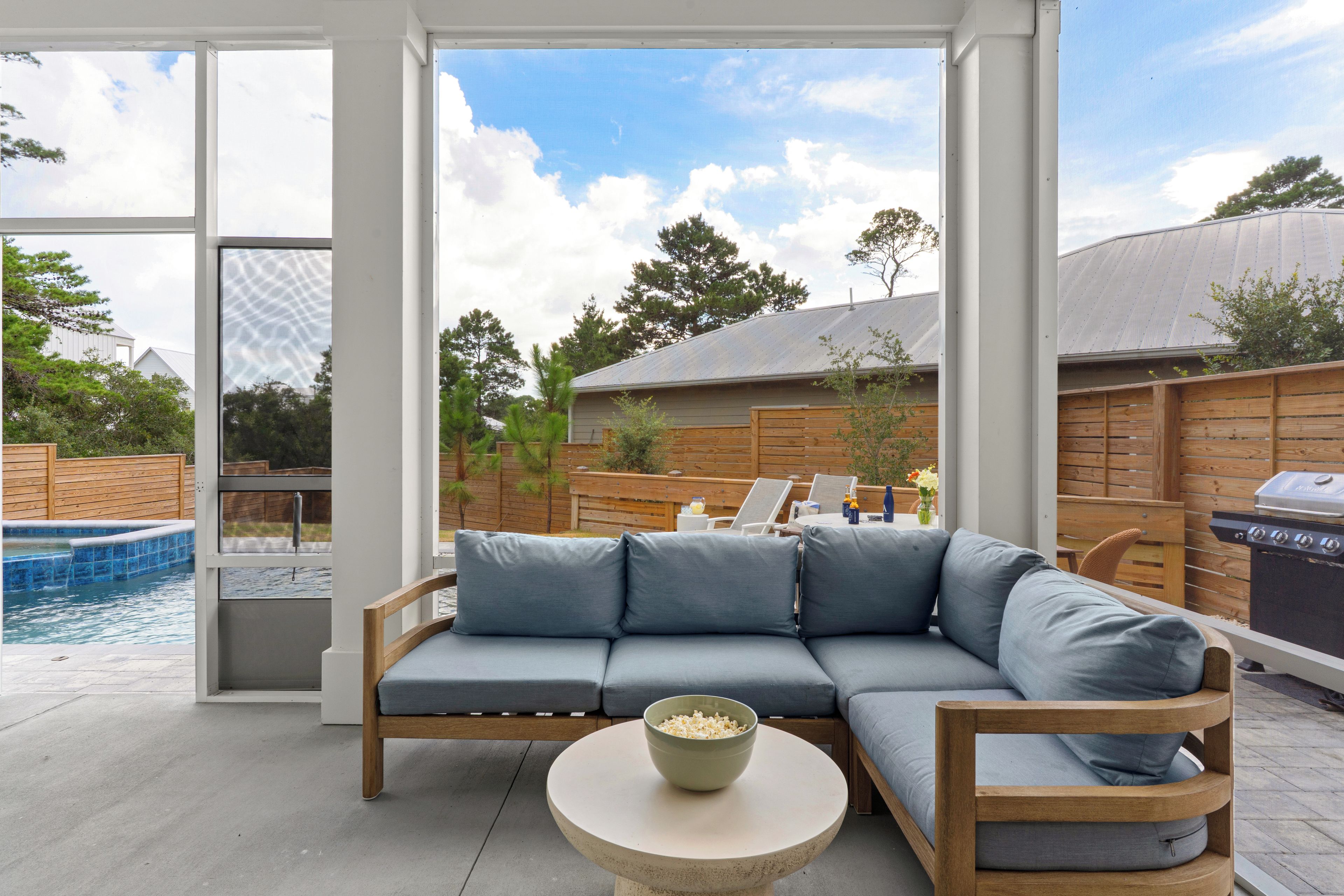 A modern outdoor seating area with a sectional sofa, a round table, and a barbecue grill.