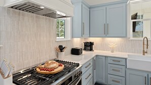 Une cuisine moderne équipée d’une cuisinière à gaz, d’une machine à café et de meubles de couleur bleu clair.