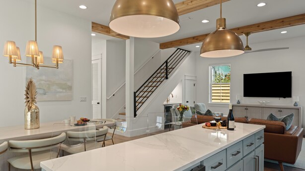 Une cuisine moderne dotée d’un îlot en marbre, de luminaires suspendus et d’un escalier menant à un niveau supérieur.