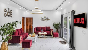 A modern living room with a red sofa, a coffee table, and a TV screen displaying 'NETFLIX'.