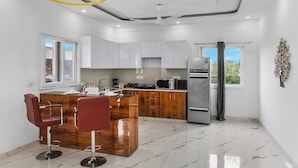 A modern kitchen with white cabinets, a wooden island, and stainless steel appliances.