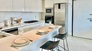 Una cocina moderna con una isla central, electrodomésticos de acero inoxidable y taburetes negros.