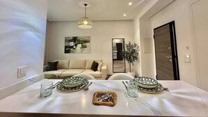 Un comedor moderno con una mesa de mármol, dos platos estampados, una jarra de vidrio y un azulejo decorativo.