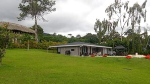 Ein Haus mit einem Strohdach, umgeben von einem gepflegten Rasen und Bäumen.