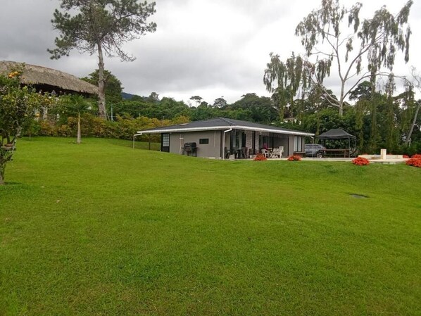 A house with a thatched roof, surrounded by a well-maintained lawn and trees.