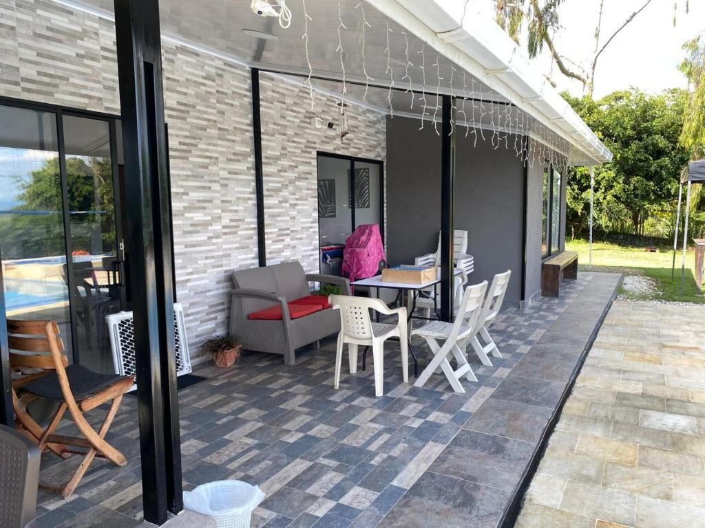 An outdoor patio with a table and chairs, a covered seating area, and a view of the outdoors.