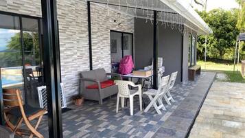 An outdoor patio with a table and chairs, a covered seating area, and a view of the outdoors.