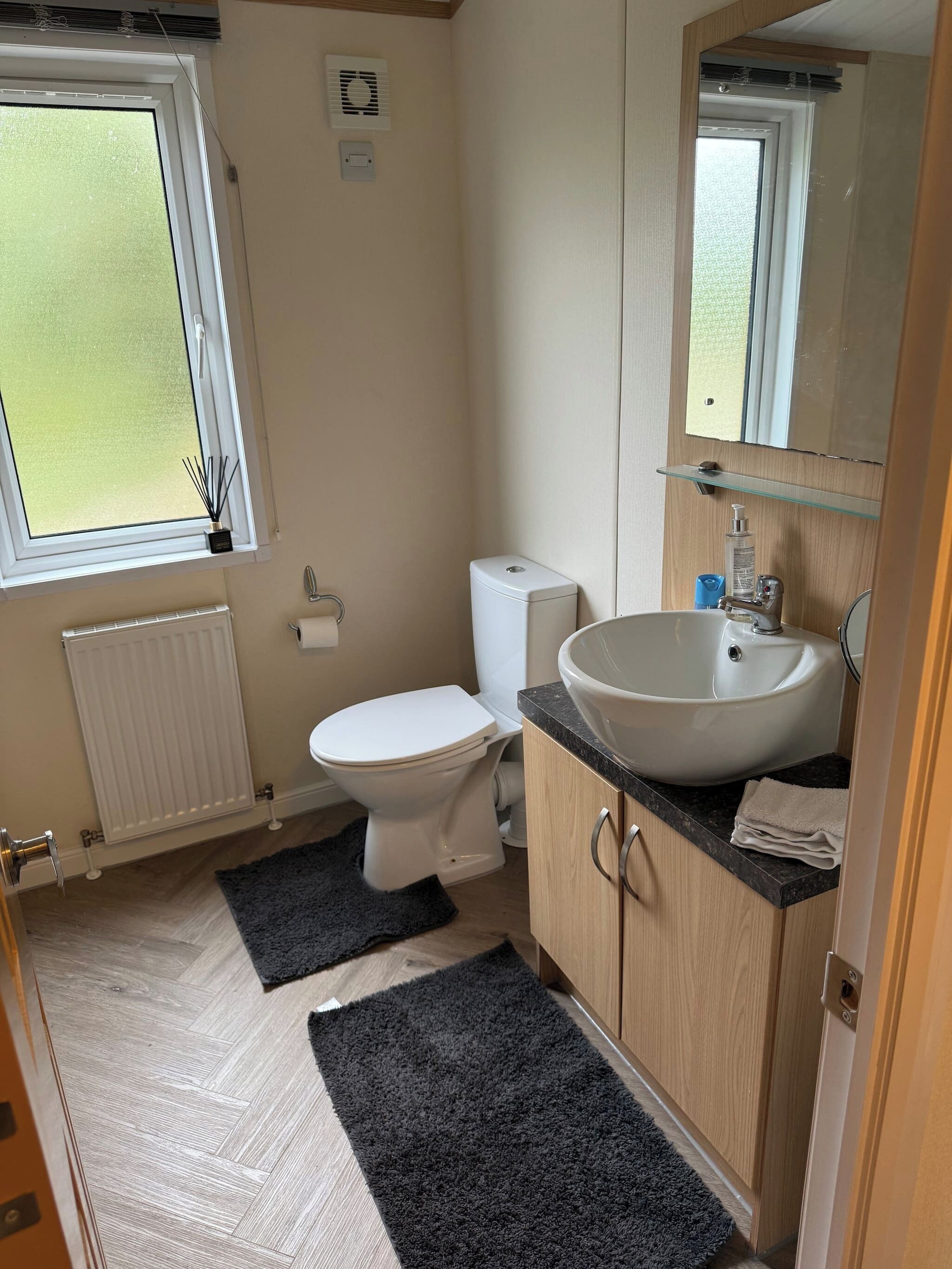 A compact bathroom with a toilet, sink, and window.