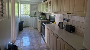 A kitchen with cabinets, a stove, a sink, and a window.