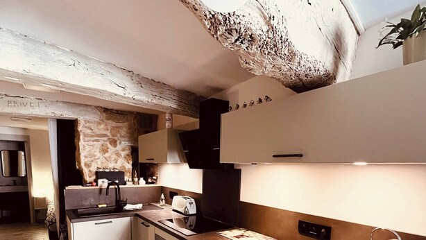 A modern kitchen with a stone accent wall, a built-in oven, and a countertop with a toaster and bread basket. - Musette du Ventoux, Studio for 3 (Bédoin)