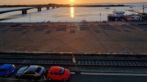 Parkkipaikka, jossa on silta, veneitä ja auringonlasku.