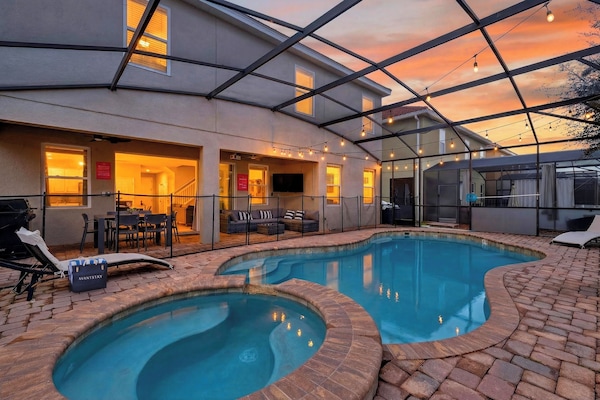 Golden-hour perfection in your screened lanai—heated pool + bubbling spa, string lights overhead, and plenty of space to lounge after the parks.
