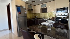 Une cuisine moderne dotée d’un îlot central, de tabourets de bar, d’un réfrigérateur, d’un four à micro-ondes, d’un four et d’un crédence décorée.