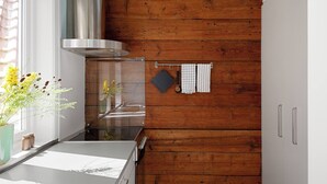 Ett kök med träpanel på väggarna, en köksfläkt i rostfritt stål, ett fönster med utsikt och en handdukshängare med handdukar.
