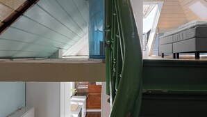 En interiör med flera nivåer, en trappa, en säng och utsikt över ett trägolv och ett fönster.