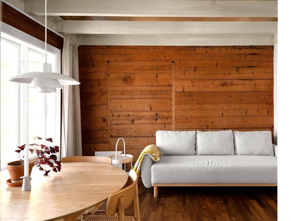 A modern living room with a wooden wall, a sofa, a dining table with chairs, and pendant lights. - Unique apartment in Stavangers most sentral square (Stavanger)