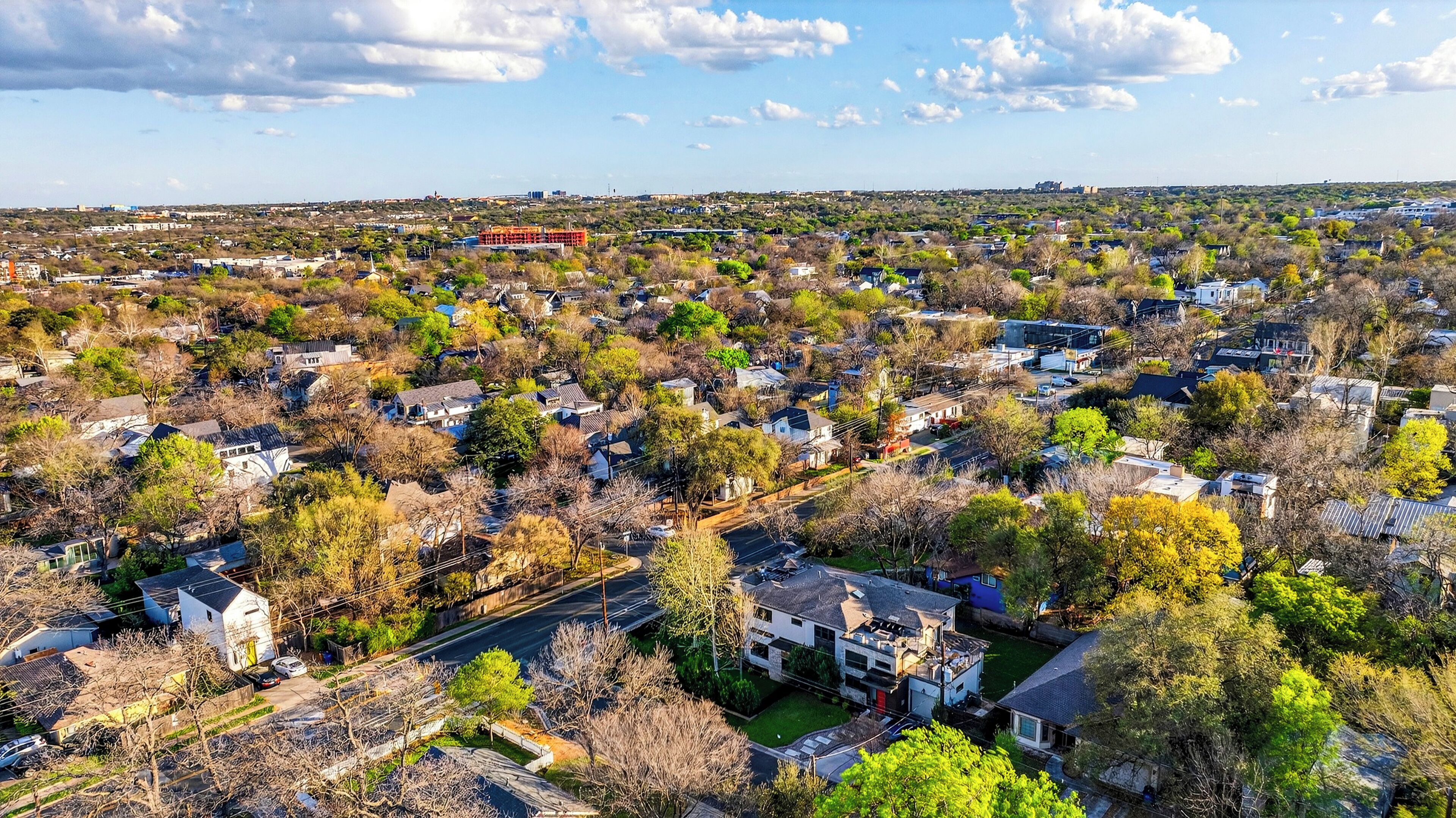 An aerial view of a residential area with houses, roads, and greenery.
