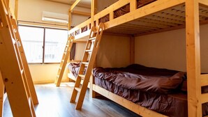 A bunk bed room with a ladder, wooden beams, and a window.