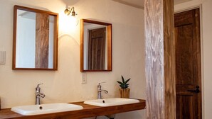 A bathroom with two sinks, wooden vanity, mirrors, and a door.
