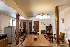 Un comedor amplio con una larga mesa de madera, rodeado de sillas, una lámpara de araña y detalles de madera.