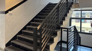 A staircase with black railings and marble-patterned walls. - Hotel Shri Ram Legacy (Jodhpur)