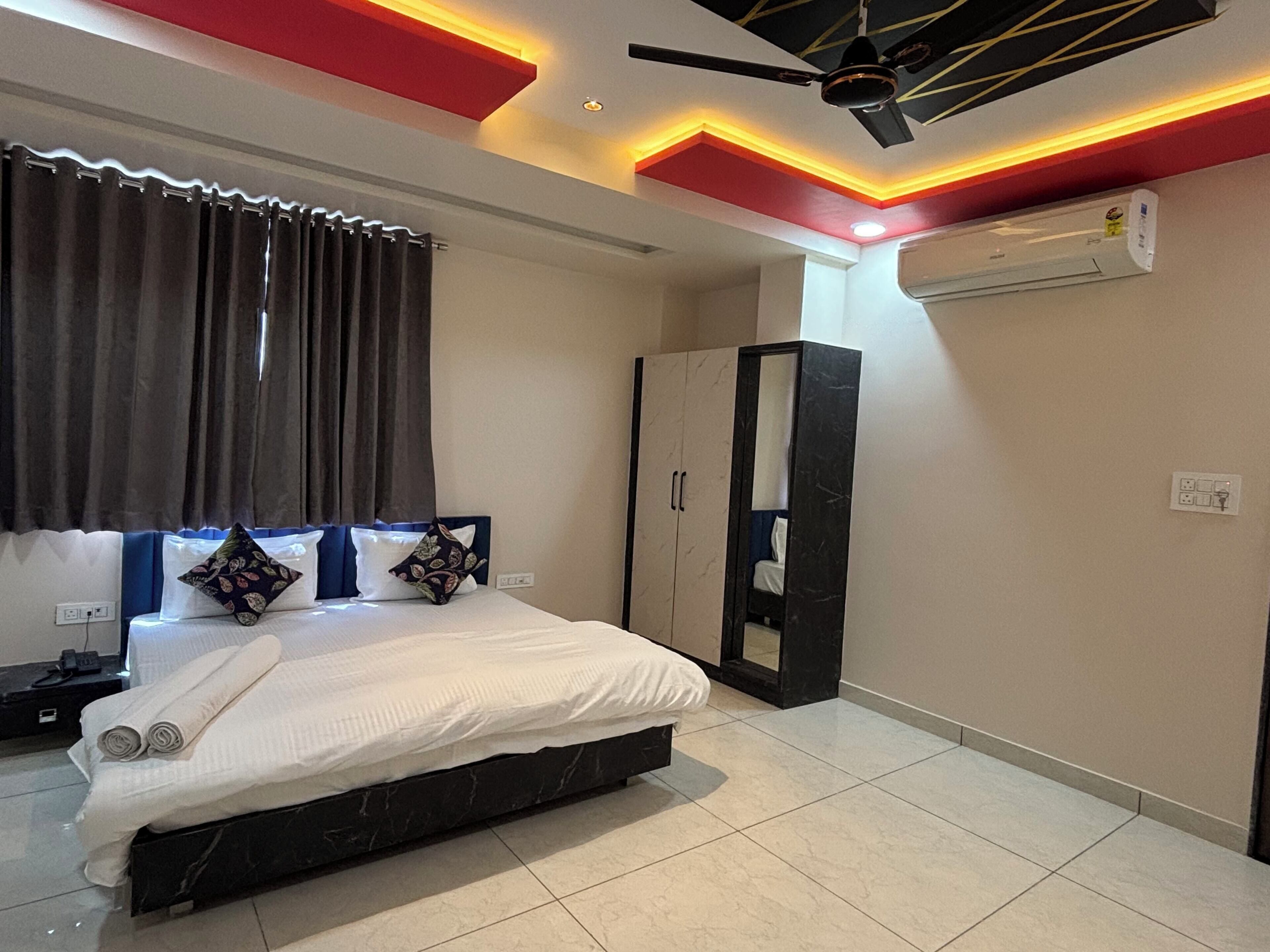 A bedroom with a bed, a wardrobe, an air conditioning unit, and a ceiling fan.