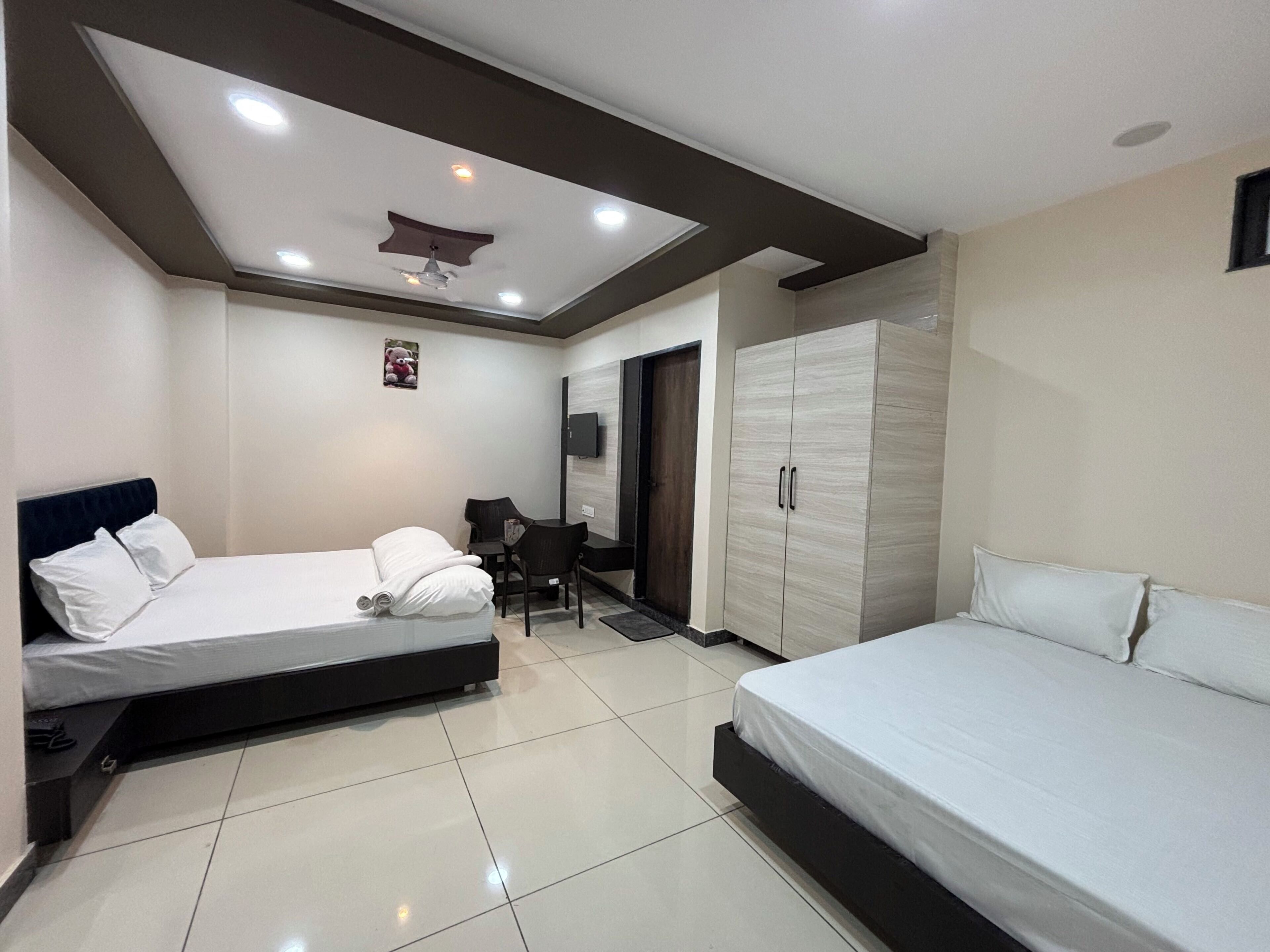 A bedroom with two beds, a desk, a chair, a wardrobe, and a ceiling fan.