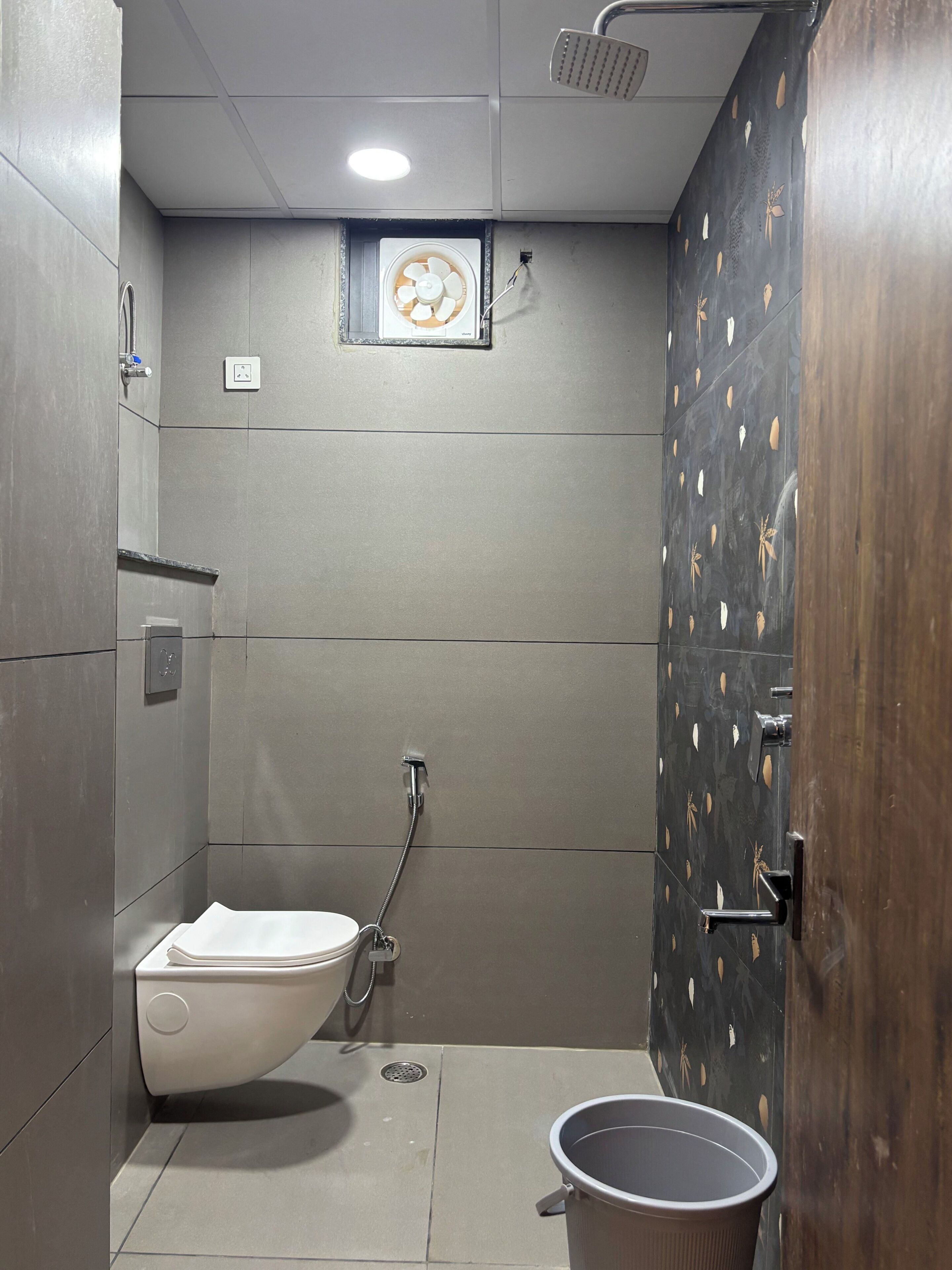 Une salle de bain moderne équipée de toilettes, d’un bidet, d’une douche et d’un seau.
