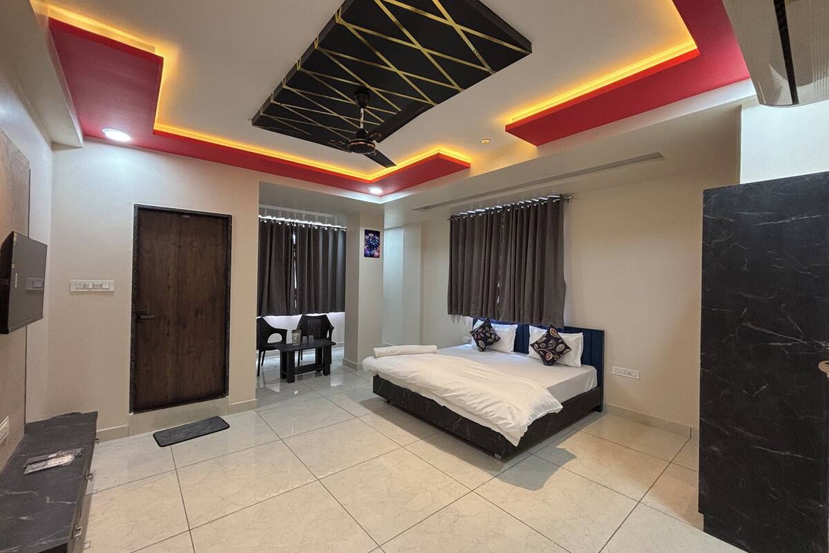 A bedroom with a bed, a desk, a chair, a ceiling fan, and a TV.