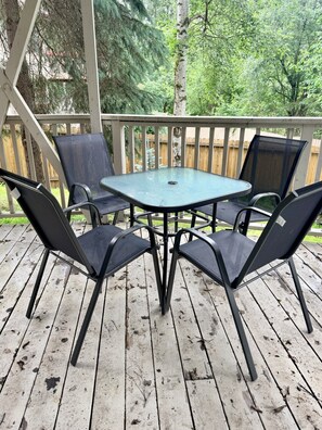 A covered outdoor patio with a square table and four chairs.