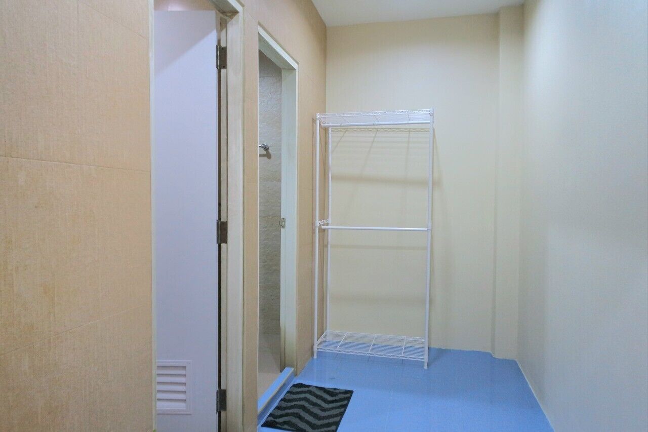 A narrow hallway with a shower area, a door, and a small rug.