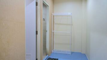 A narrow hallway with a shower area, a door, and a small rug.