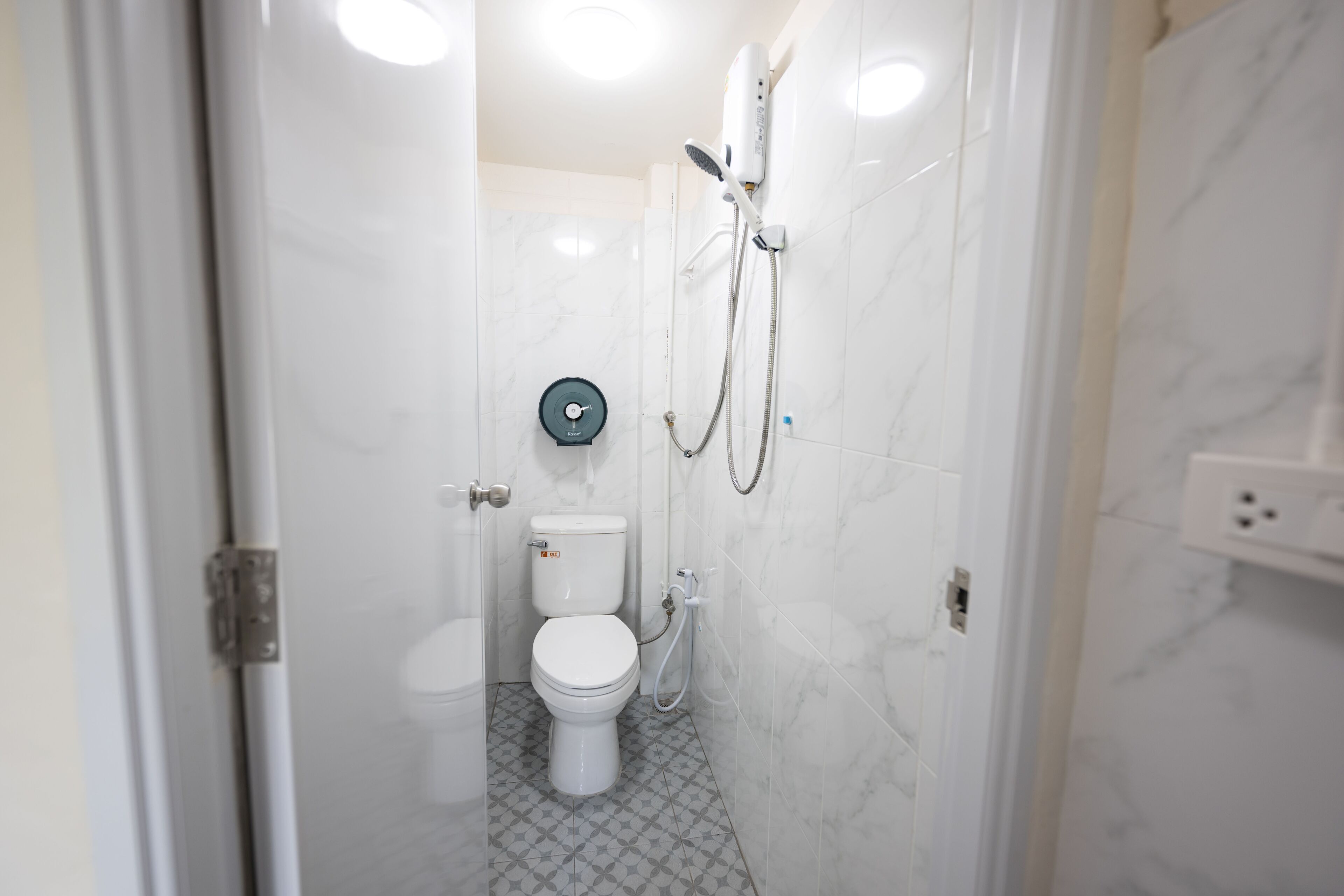 A bathroom with a toilet, a shower, and a toilet paper holder.