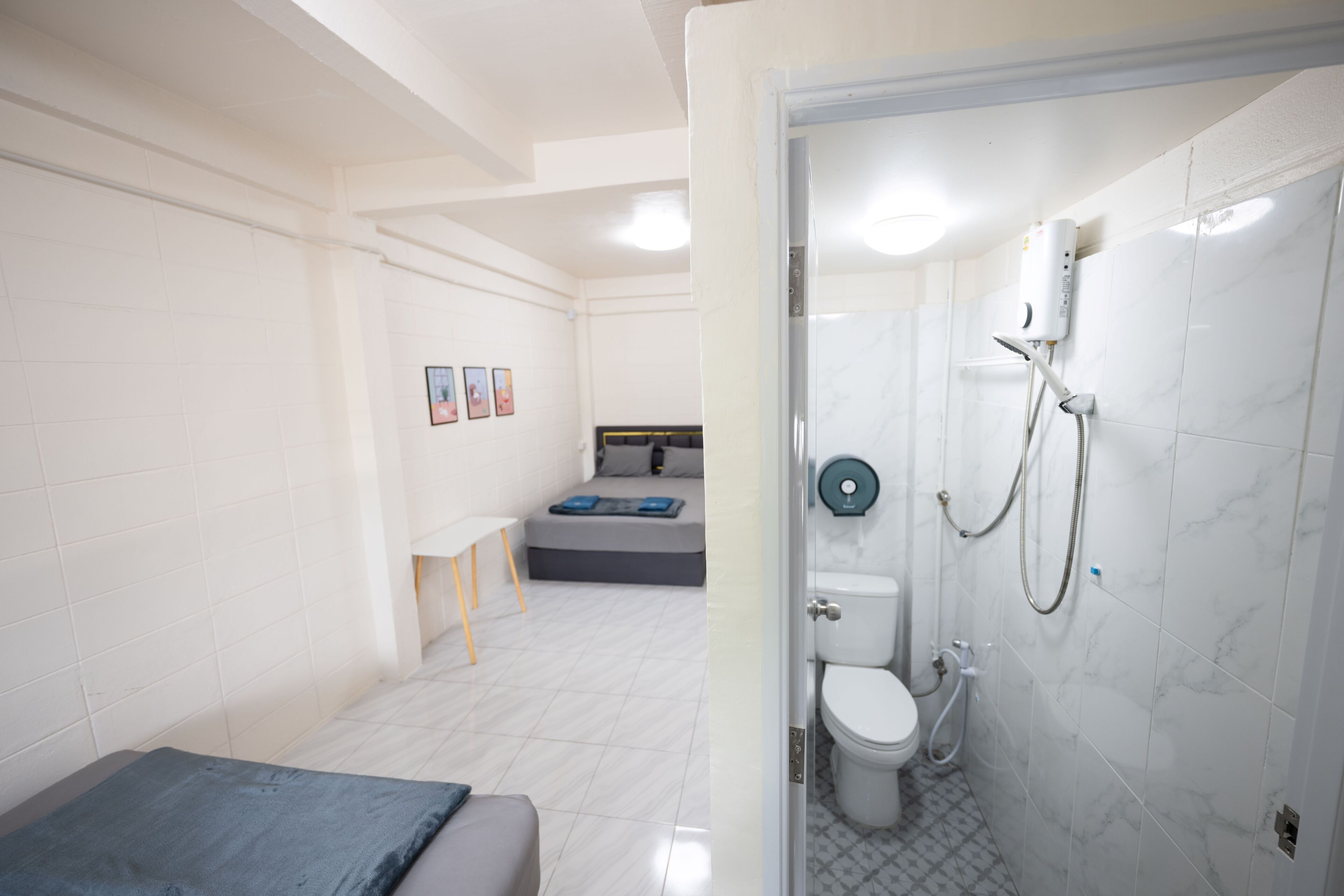 Ein modernes Badezimmer mit Dusche, Toilette und einem Bett mit blauer Decke.