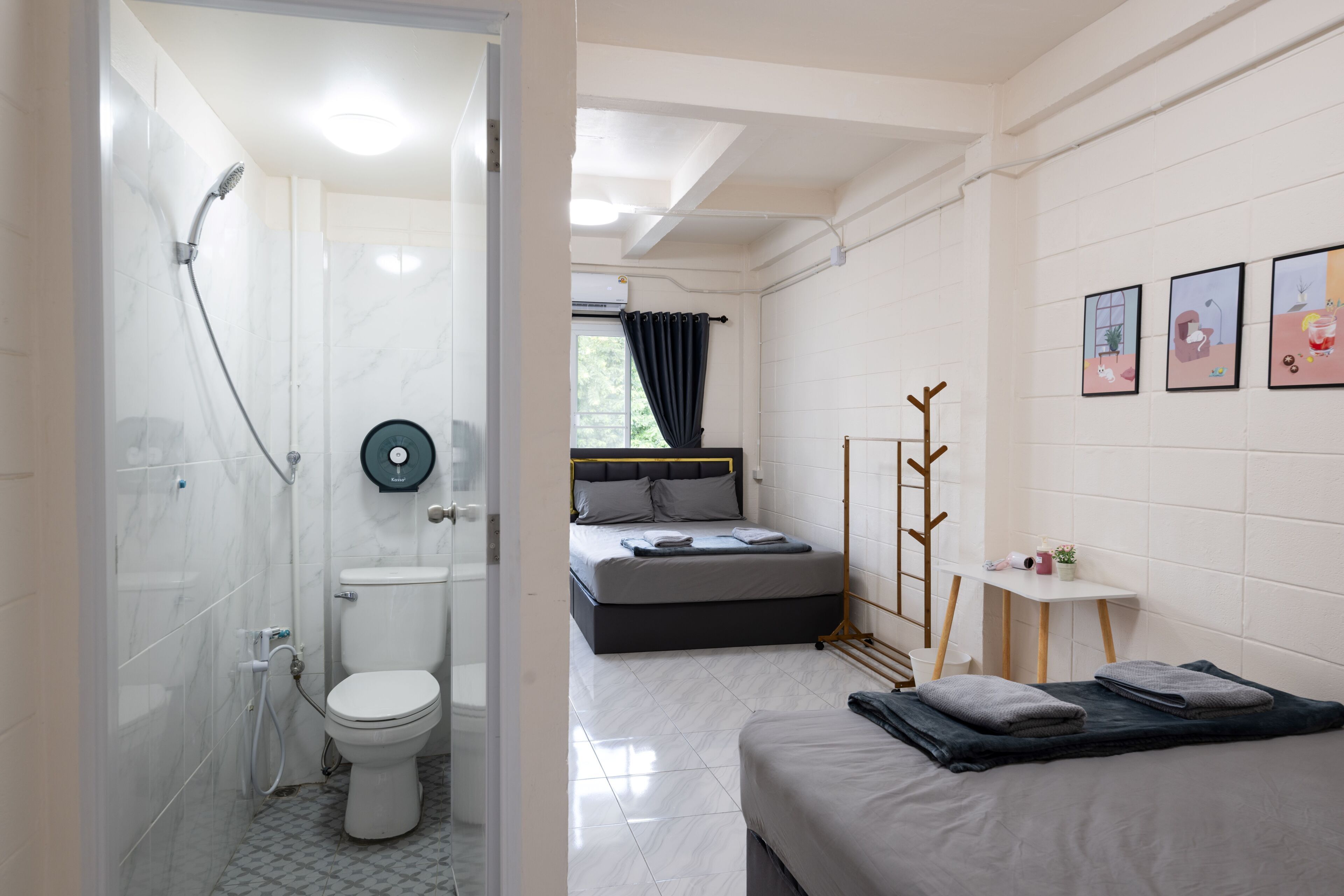 A modern bathroom with a shower, toilet, and a bed with a bedside table.