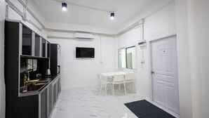 Una cocina compacta con comedor, una puerta blanca y un televisor montado.