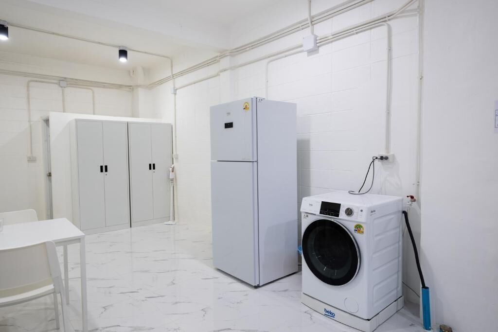 Un cuarto de lavandería con lavadora, refrigerador y una mesa.