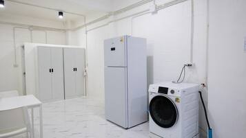 Un cuarto de lavandería con lavadora, refrigerador y una mesa.