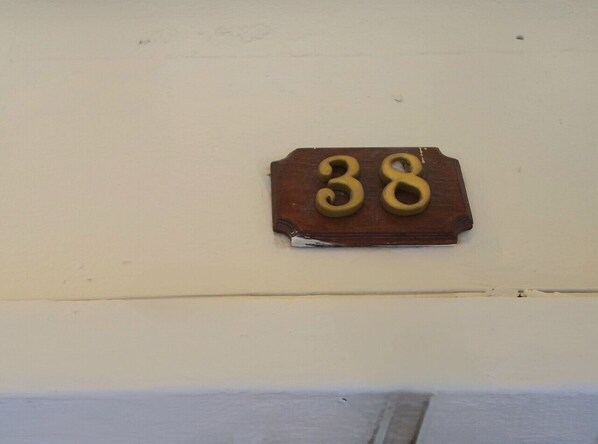 A wooden house number plaque with the number 38 on a white wall. - At 38 Don Mueang (Bangkok)