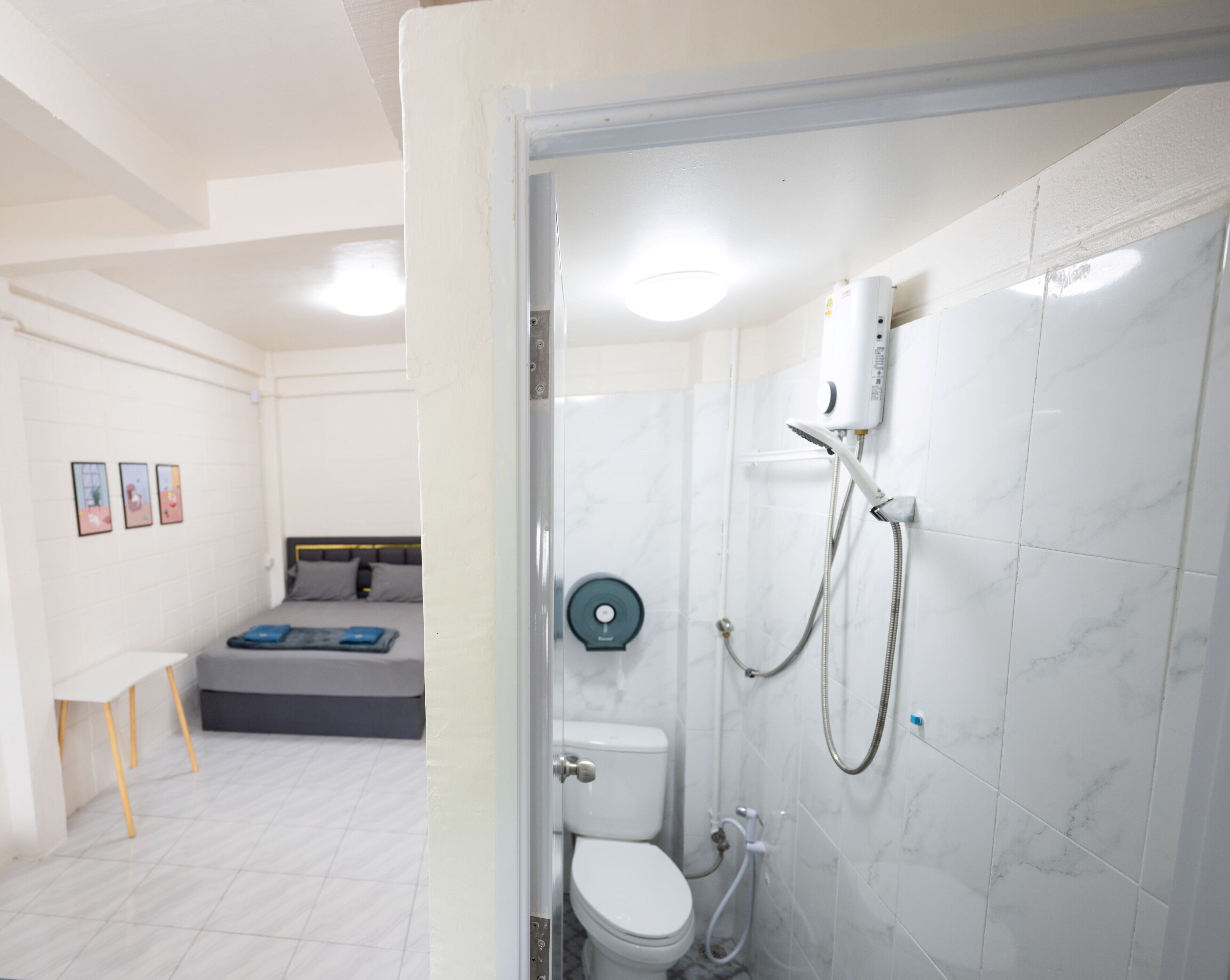 Un baño moderno con ducha, inodoro y una cama en la habitación contigua.
