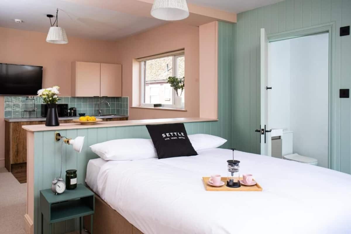A bedroom with a bed, bedside table, lamp, and a tray with a cup and saucer.