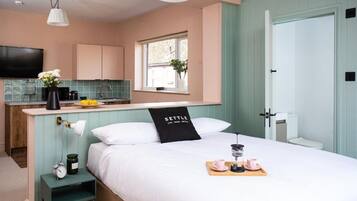 A bedroom with a bed, bedside table, lamp, and a tray with a cup and saucer.
