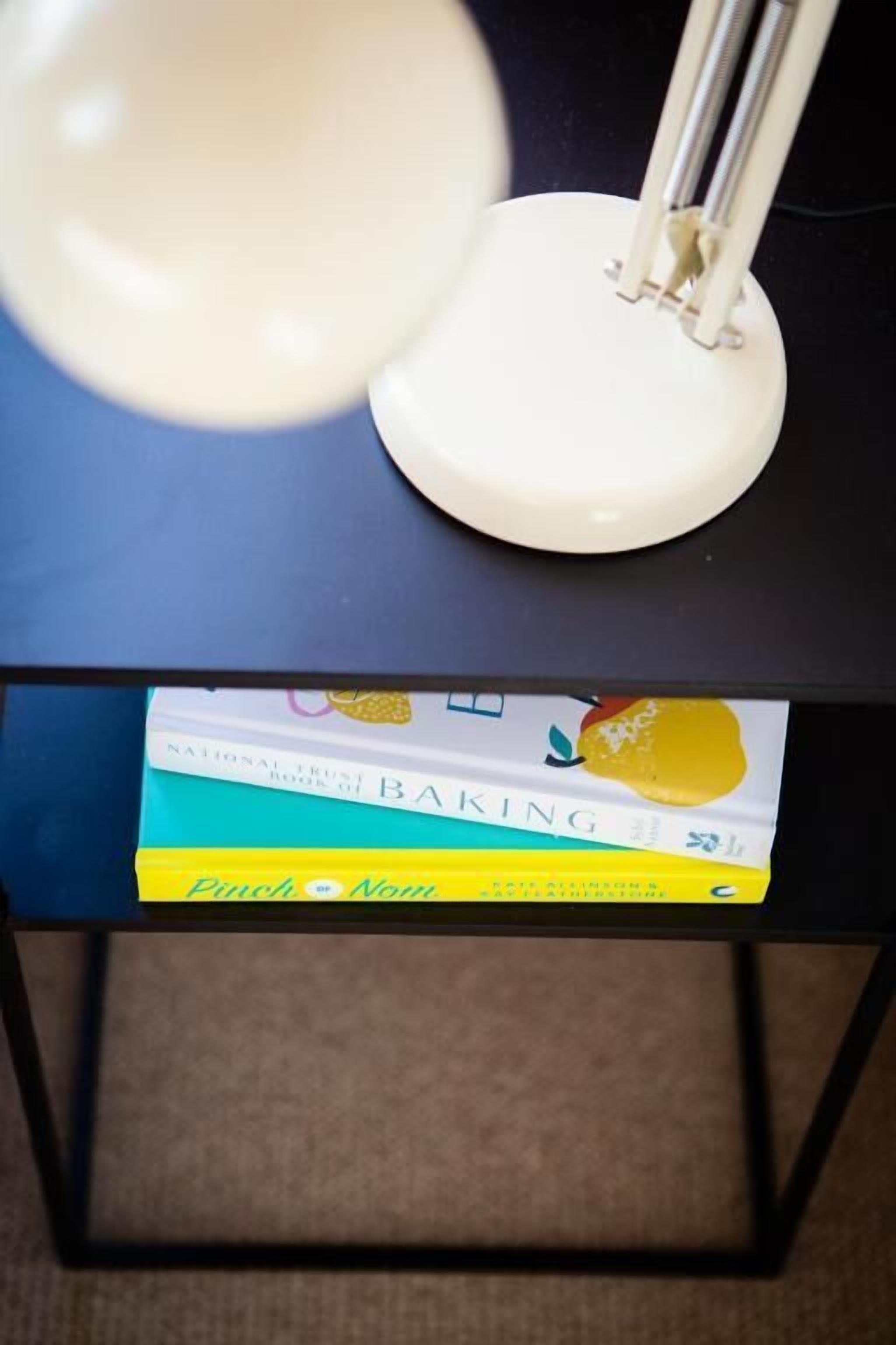Uma mesa com uma luminária, um livro intitulado 'BAKING' e um caderno amarelo.