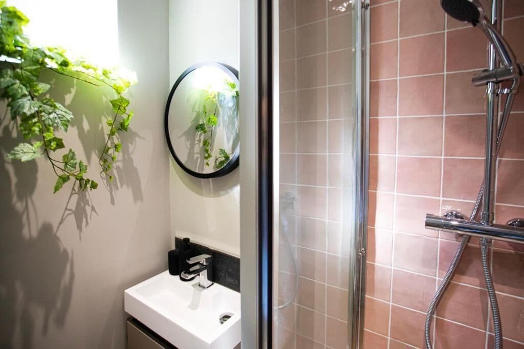 A bathroom with a white sink, a mirror, and a shower with a glass door.